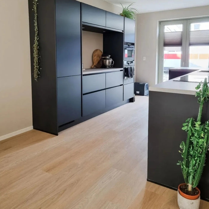 Vivafloors 7810 click pvc vloer met rechte planken in keuken met zwarte kastwand en veel daglicht.